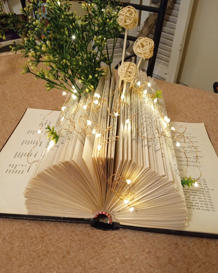 an open book sitting on top of a table next to a vase filled with flowers