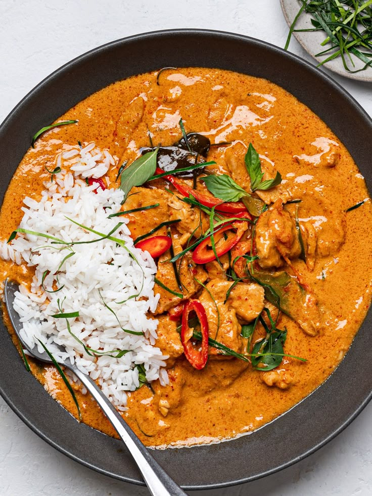 a plate with rice, meat and veggies on it next to a spoon