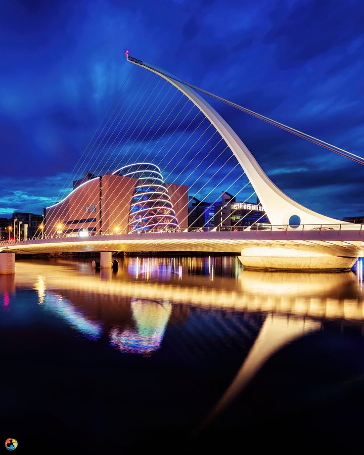 a bridge that is over water with buildings in the background and clouds in the sky