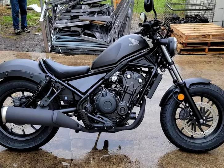 a black motorcycle parked on top of a wet ground next to a pile of pallets