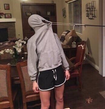 a person standing in front of a dining room table wearing a hoodie and shorts