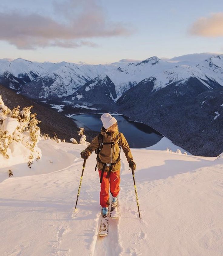 a man riding skis down the side of a snow covered slope on top of a mountain