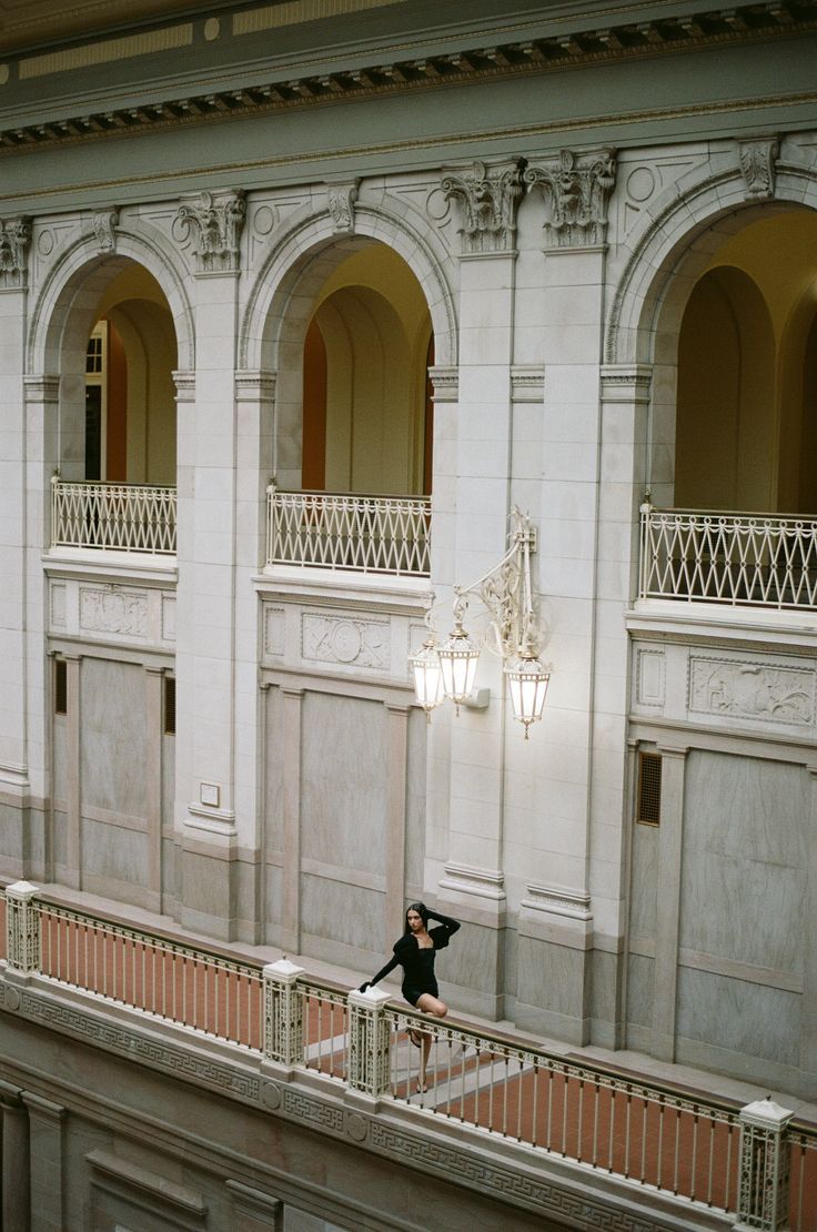 a woman standing on the balcony of an old building with arches and balconies