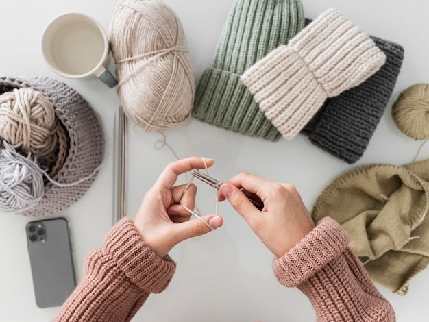 someone is knitting yarn on the table with their cell phone and other items around them