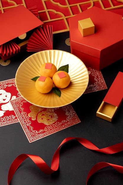 two oranges are in a bowl on a table next to red boxes and ribbon