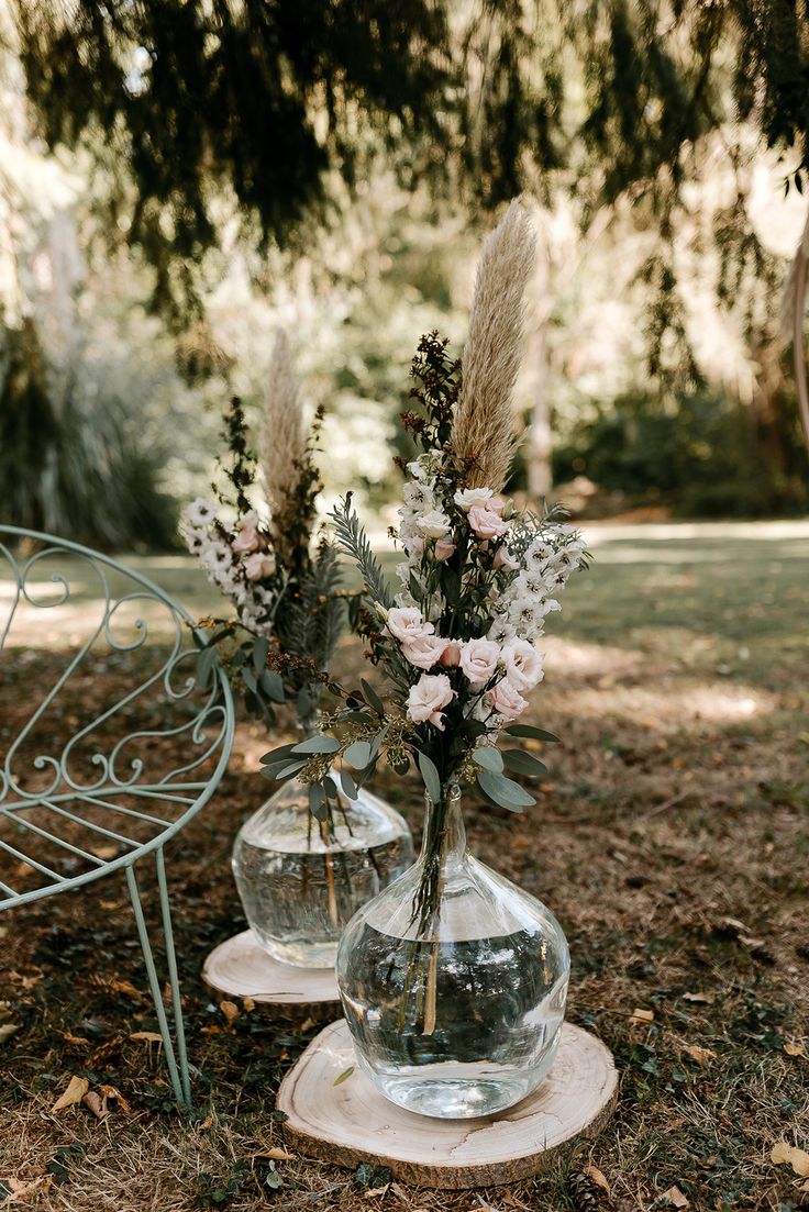 two vases filled with flowers sitting on top of a tree stump