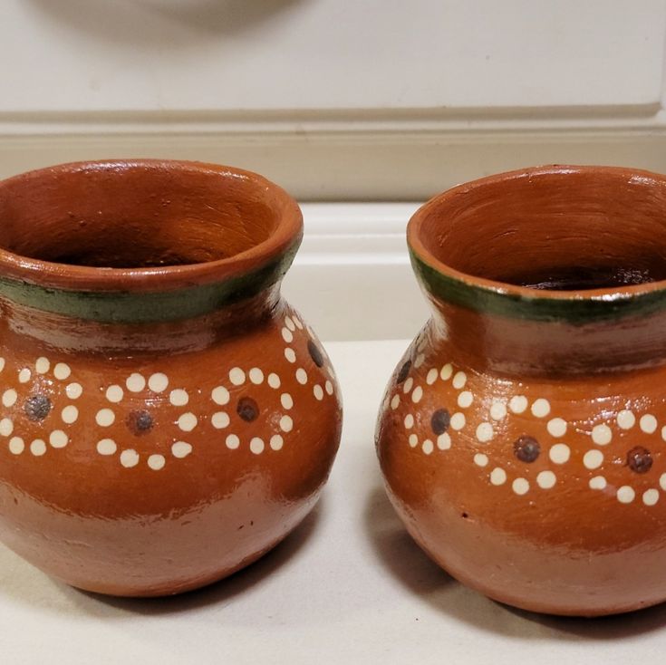 two brown vases sitting next to each other on a counter