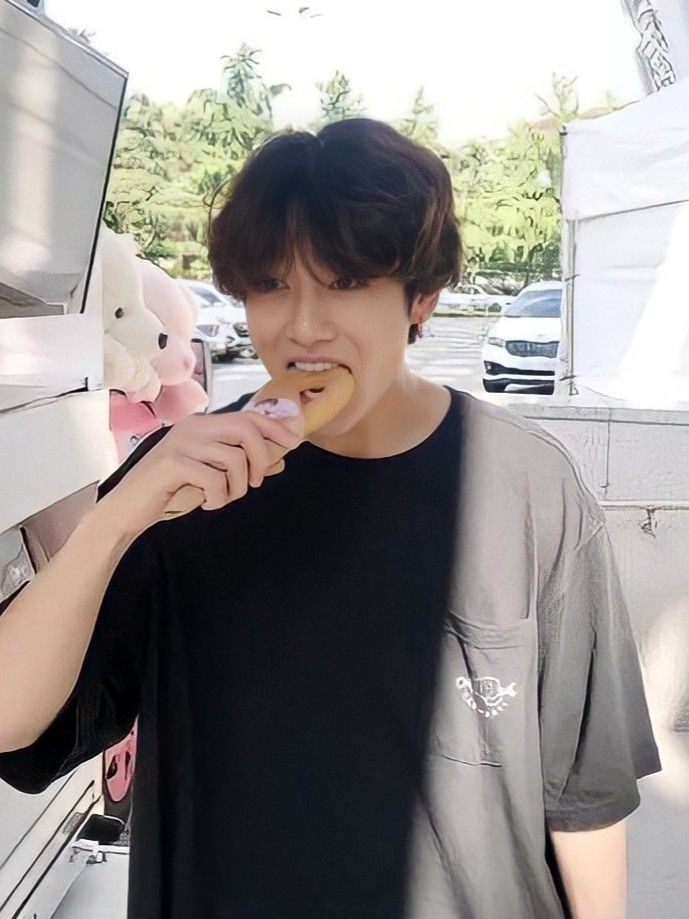 a young man is eating something out of his mouth while standing in front of an ice cream truck