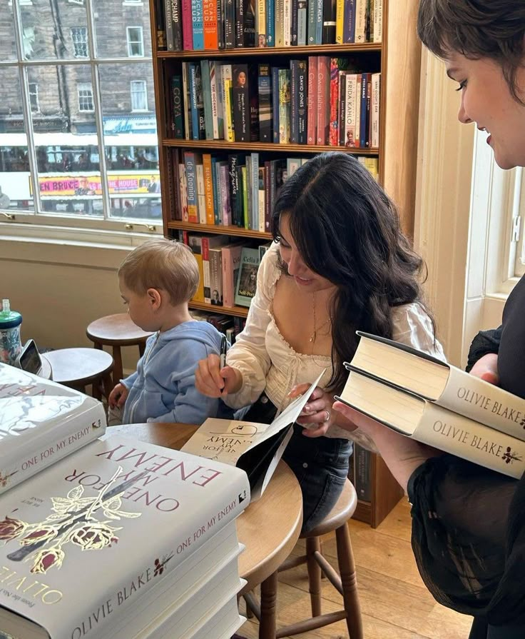 two women sitting at a table with books in front of them and one woman reading