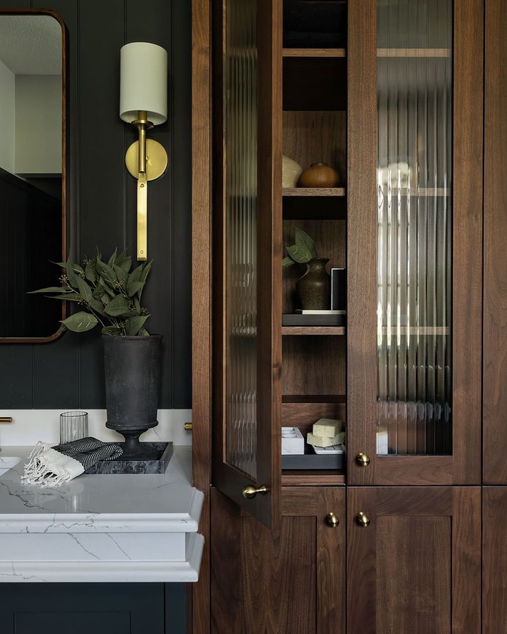 a bathroom with dark wood cabinets and white counter tops, along with a mirror on the wall