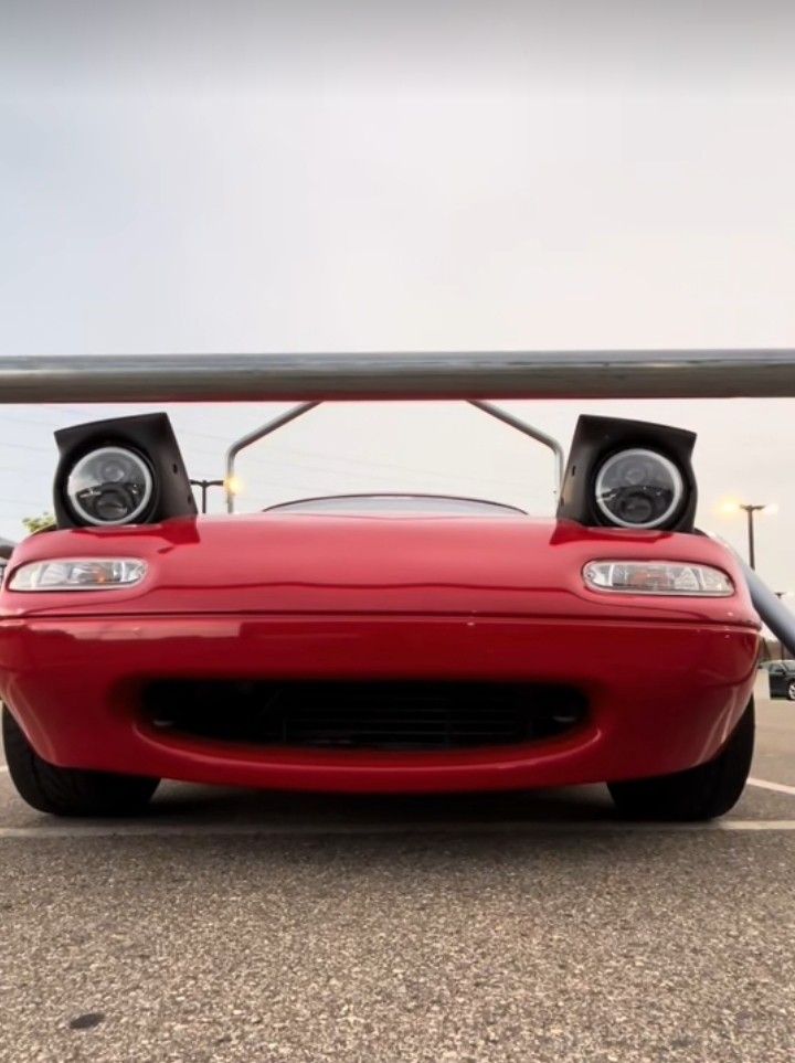 the front end of a red sports car with two speakers on it's roof