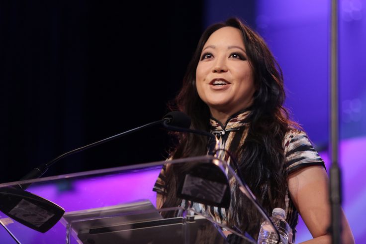 a woman standing at a podium in front of a microphone