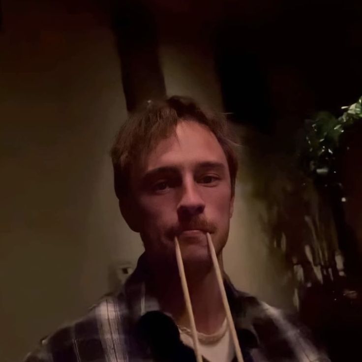 a man with a stick in his mouth is making a funny face at the camera