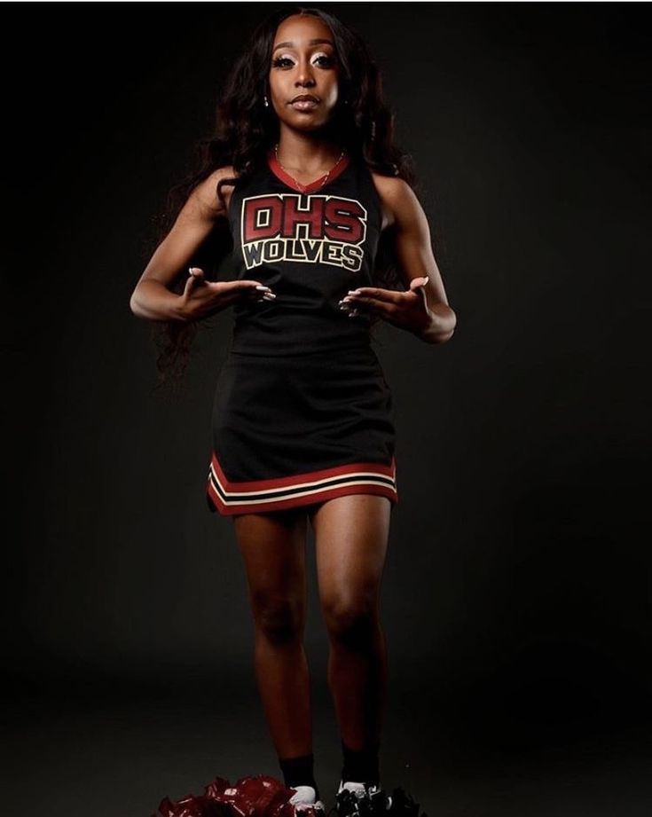 a woman in a cheerleader uniform is posing for a photo with her hands on her hips