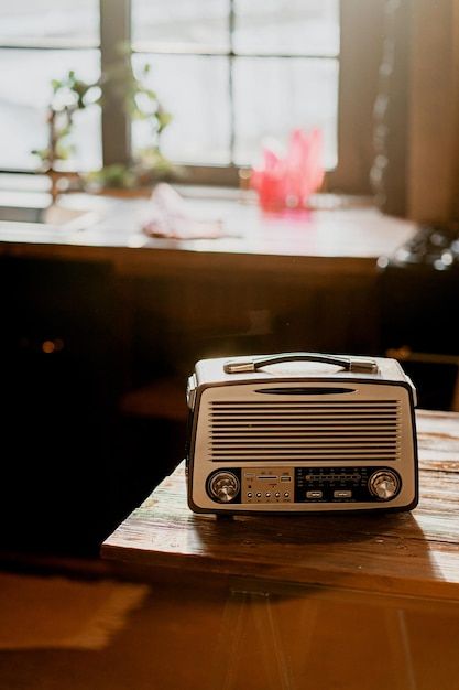 an old fashioned radio sitting on top of a wooden table in front of a window