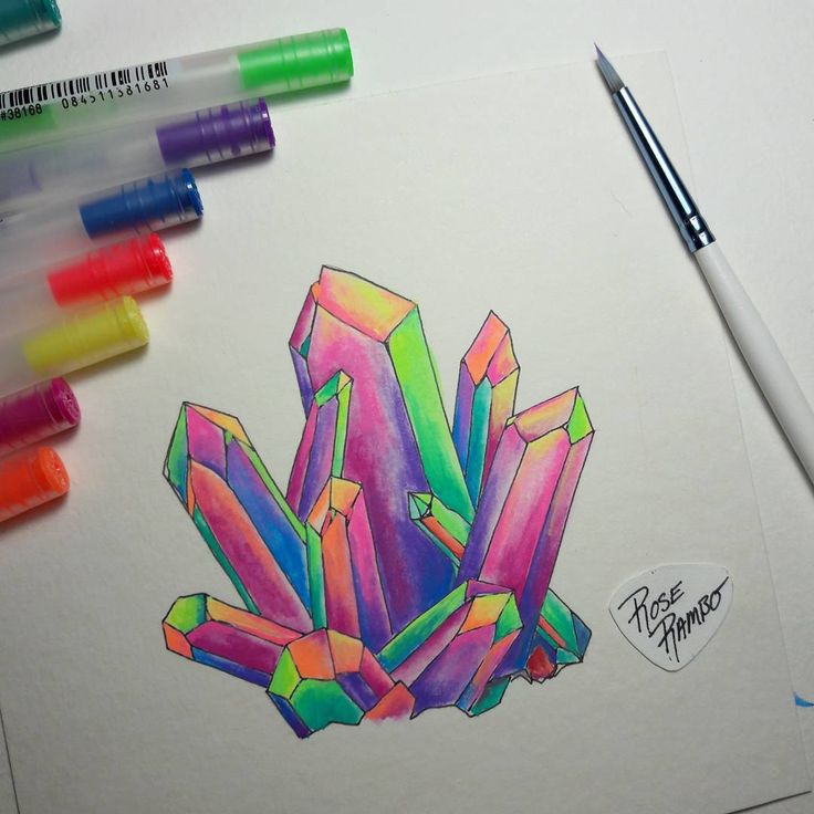 colored pencils and markers are next to a drawing of a cluster of crystal stones