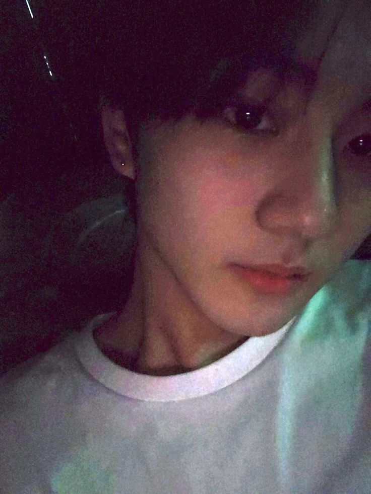 a woman with dark hair and white shirt looking at the camera while she's taking a selfie