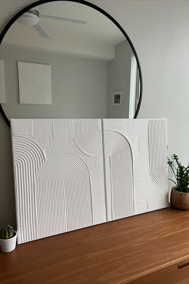 a mirror sitting on top of a wooden table next to a potted succulent