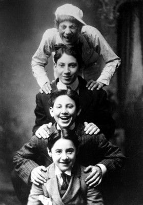 an old black and white photo of four people posing for the camera with their arms around each other