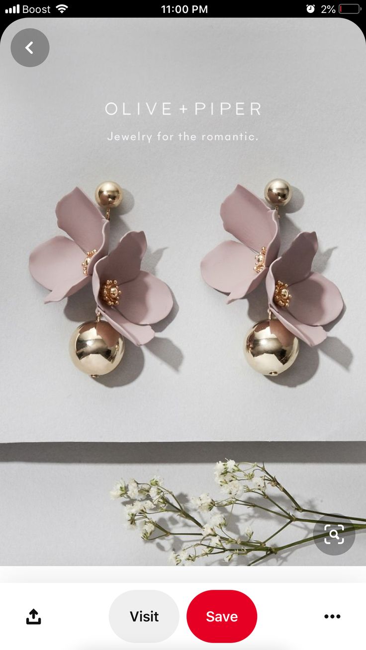 two pairs of pink and gold flower earrings on top of a white box with flowers