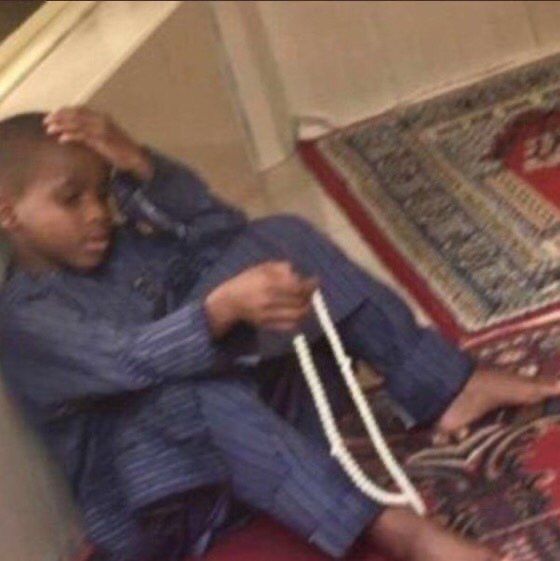 a young boy sitting on the floor with a rope around his neck