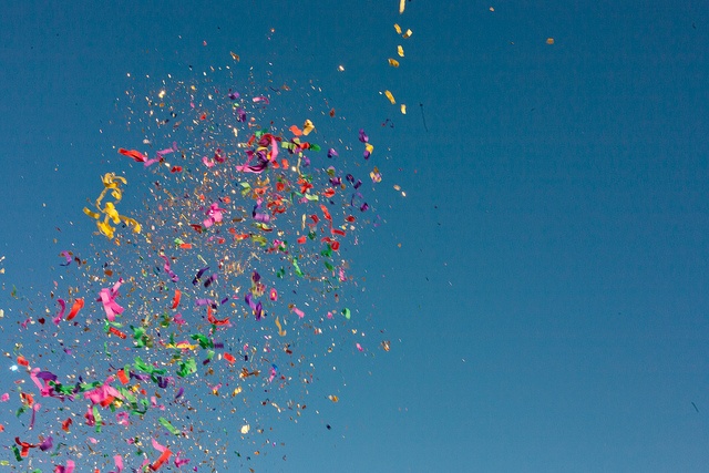 a bunch of colorful confetti and streamers are in the air on a sunny day