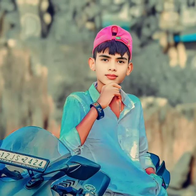 a young boy sitting on top of a motorcycle wearing a pink hat and blue shirt