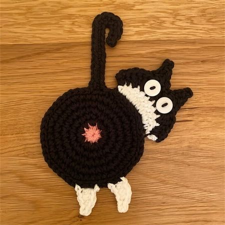 two crocheted black and white cats on wooden floor