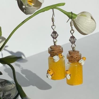 there are two jars with honey on them hanging from the hooks, next to a plant