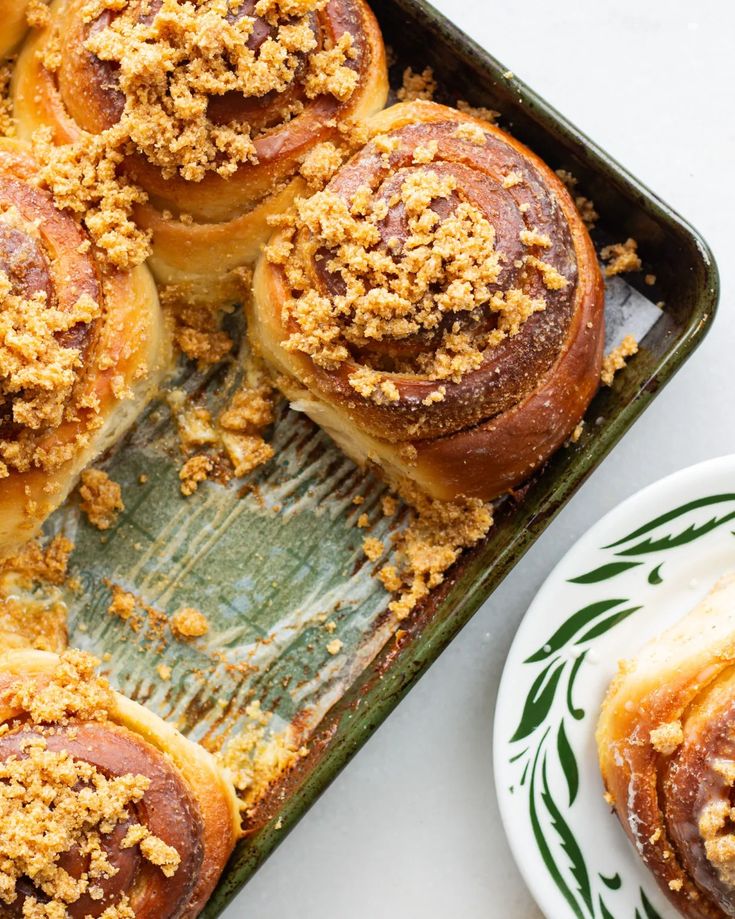 baked pastries in a baking pan with butter on top and plate next to it