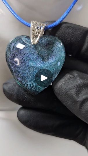 a heart shaped pendant is being held by a glove