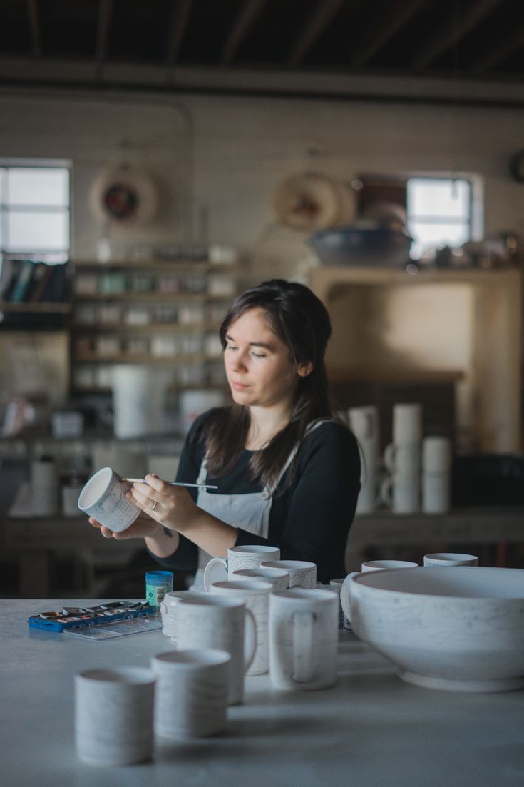 a woman sitting at a table with cups