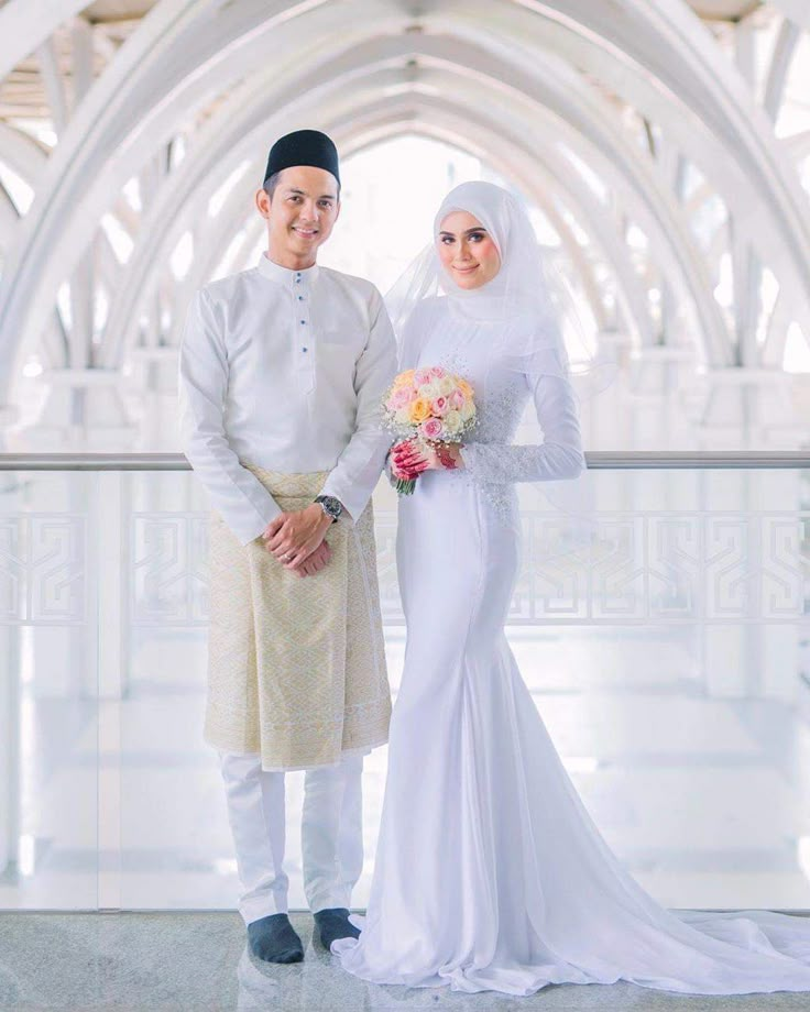 a man and woman standing next to each other in front of a white building with arches