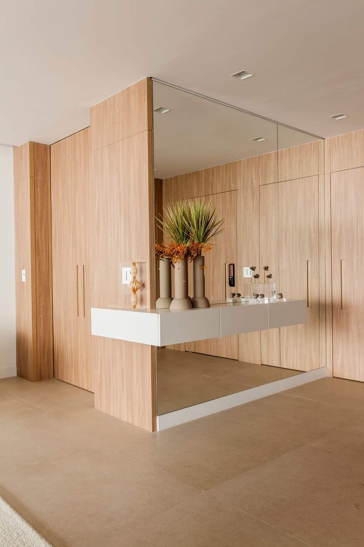 a large mirror in the middle of a room with vases and plants on it