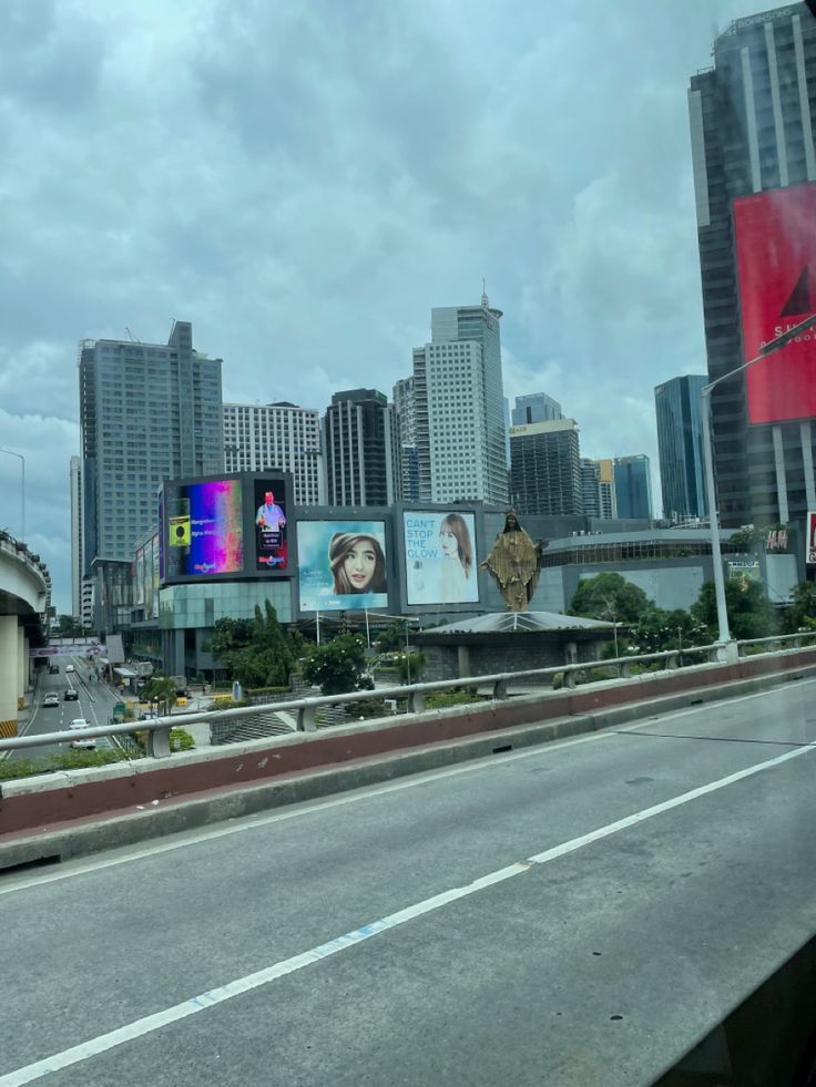 an empty highway with billboards on the side and buildings in the backgroud