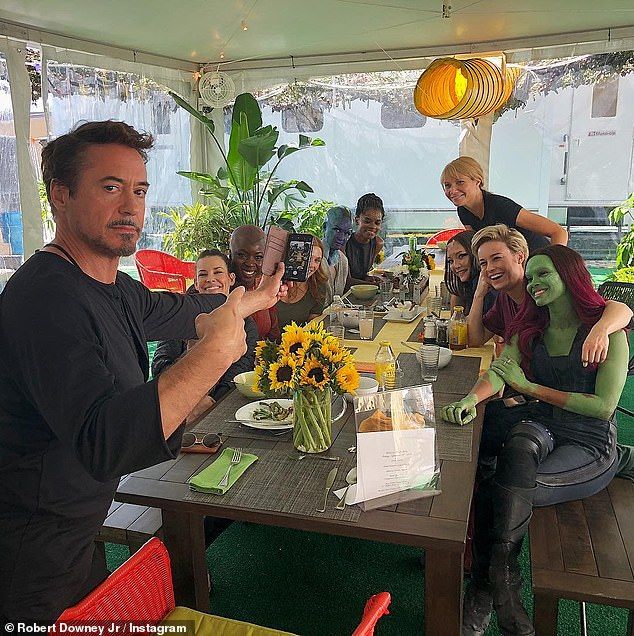 a group of people sitting around a table with plants and flowers in vases on it