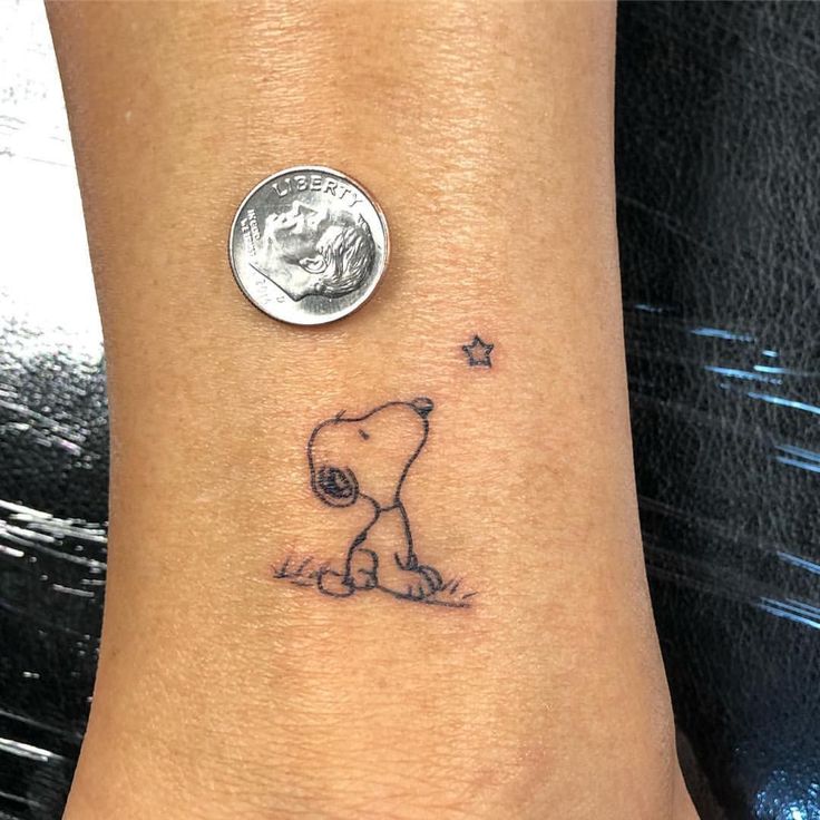 a small tattoo on the ankle of a person with a coin in front of them