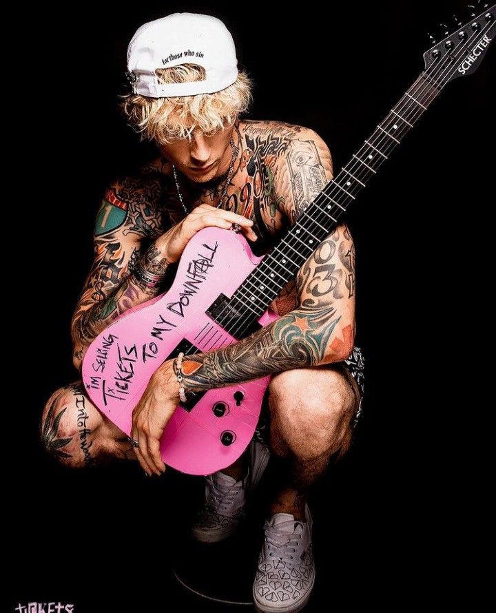 a man with tattoos holding a pink guitar