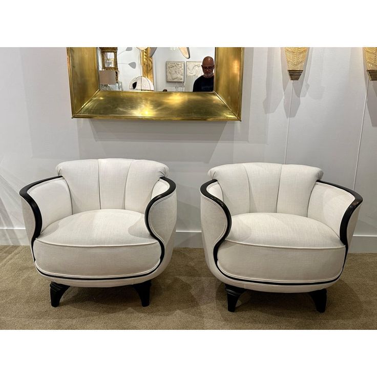 two white chairs sitting next to each other in front of a mirror