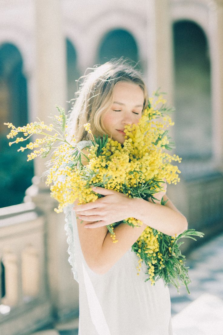 a woman in white dress holding yellow flowers