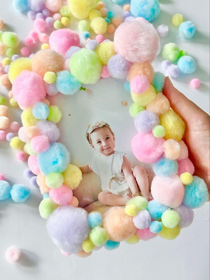 a baby is surrounded by pom - poms in the shape of a heart