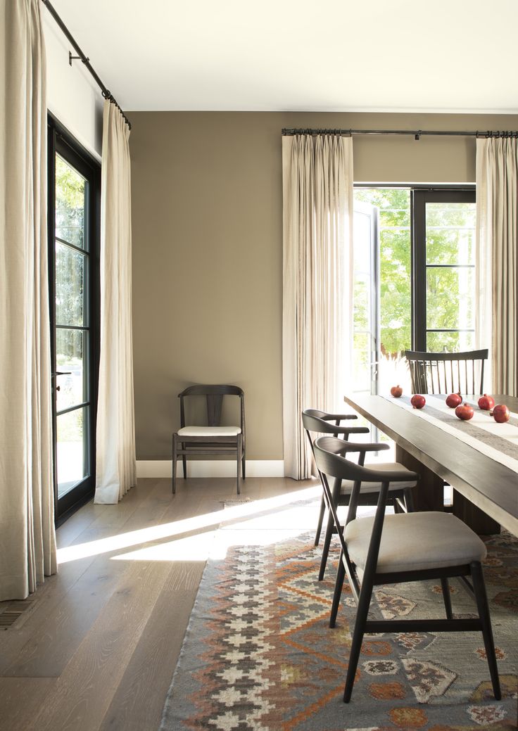 a dining room table with chairs and an area rug in front of the door that leads to another room