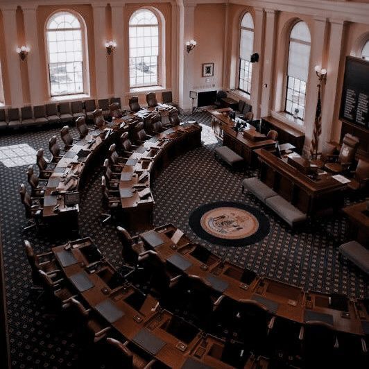 an aerial view of a large room filled with wooden chairs and desks in front of two big windows