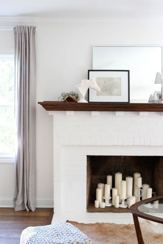 a fireplace with candles and pictures on the mantle