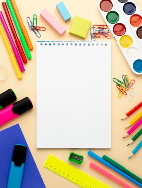 an open notebook surrounded by school supplies such as markers, pencils, markers and crayons