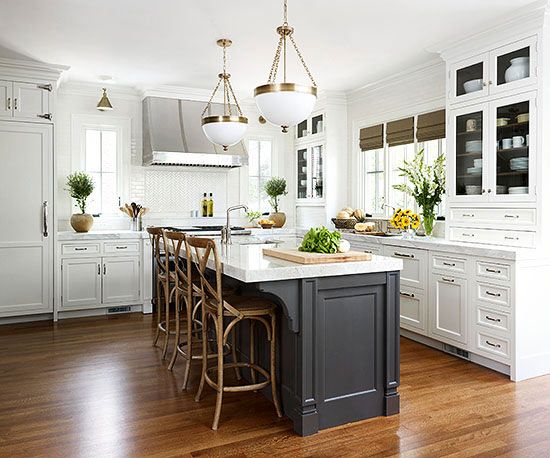 a large kitchen with white cabinets and wooden flooring, along with an island in the middle