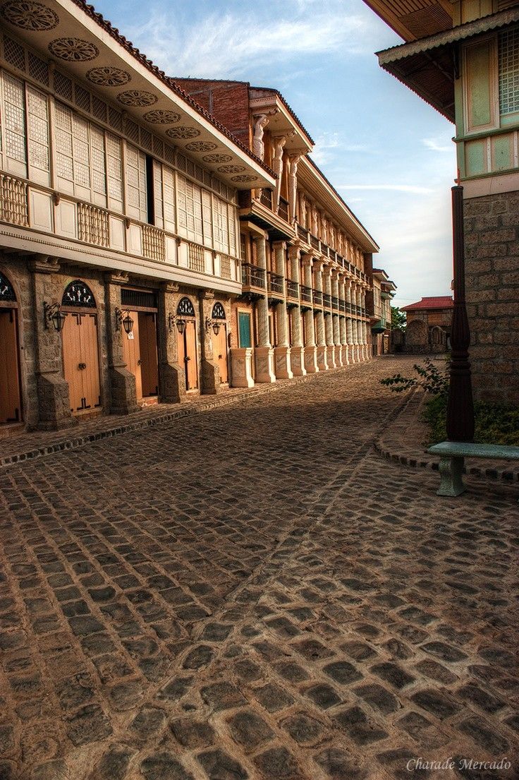 a cobblestone street in front of an old building with wooden doors and windows