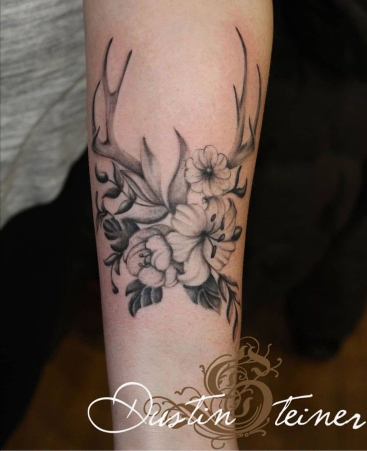 a woman's arm with flowers and antlers on it