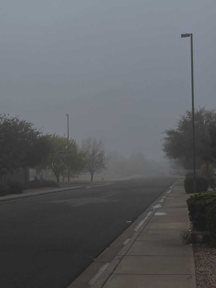 an empty street on a foggy day with no cars or people in the distance