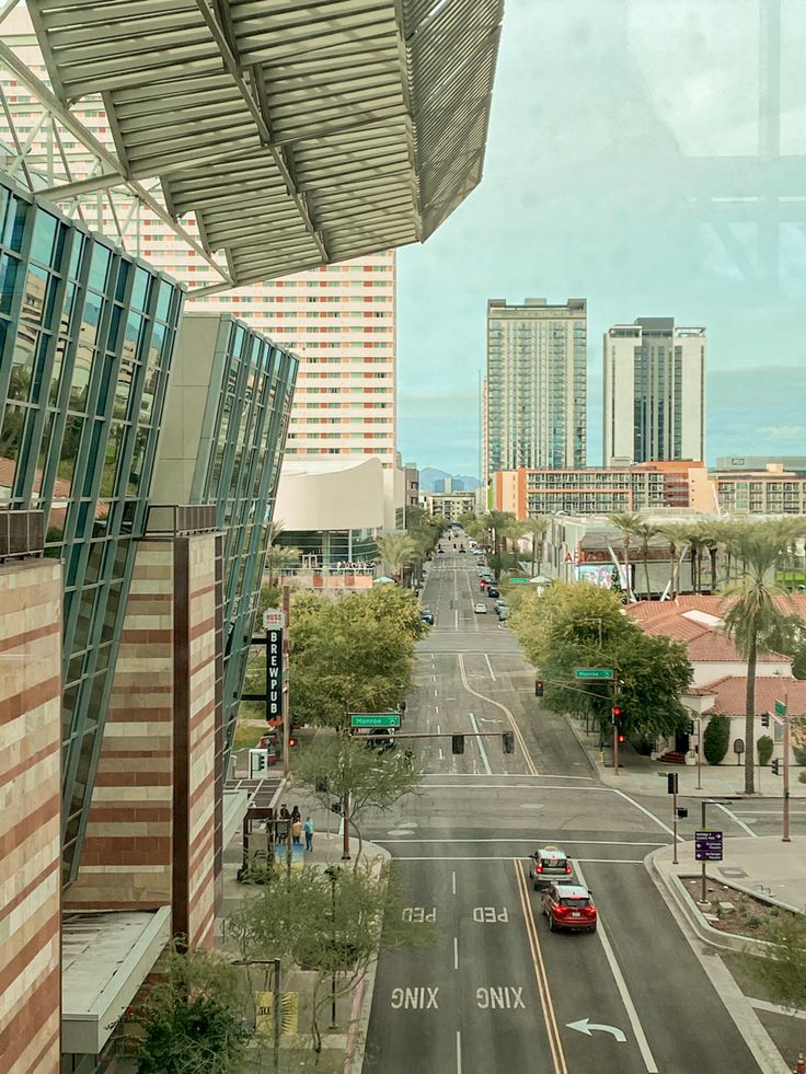 an empty city street with tall buildings on both sides and cars driving down the road